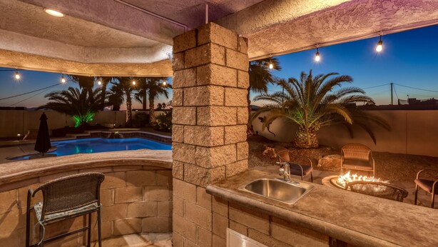 An outdoor kitchen area with a pool, stone walls, and a fire pit. - Private Backyard w/Outdoor Kitchen & Boat Parking! (Lake Havasu City)