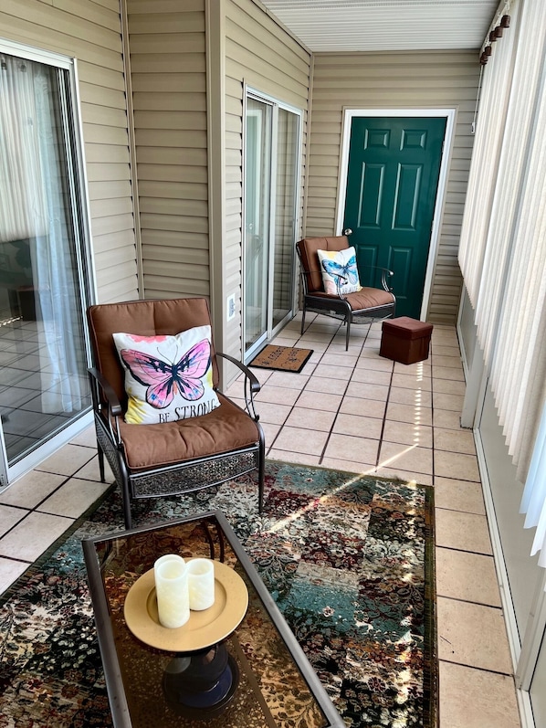 Relax on the covered porch with comfortable seating and a small table for a peaceful retreat.