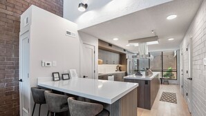 A modern kitchen with a central island, bar stools, and a view of the adjacent living area. - Park Avenue Condos by Park City Vacations (Park City)