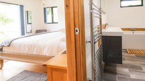A modern bedroom with a bed, bedside table, and a view of the outdoors. - No1 The Lodge (Bishops Castle)
