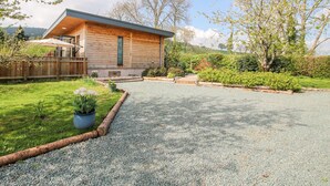 A modern wooden house with a gravel driveway, surrounded by lush greenery and trees. - No1 The Lodge (Bishops Castle)