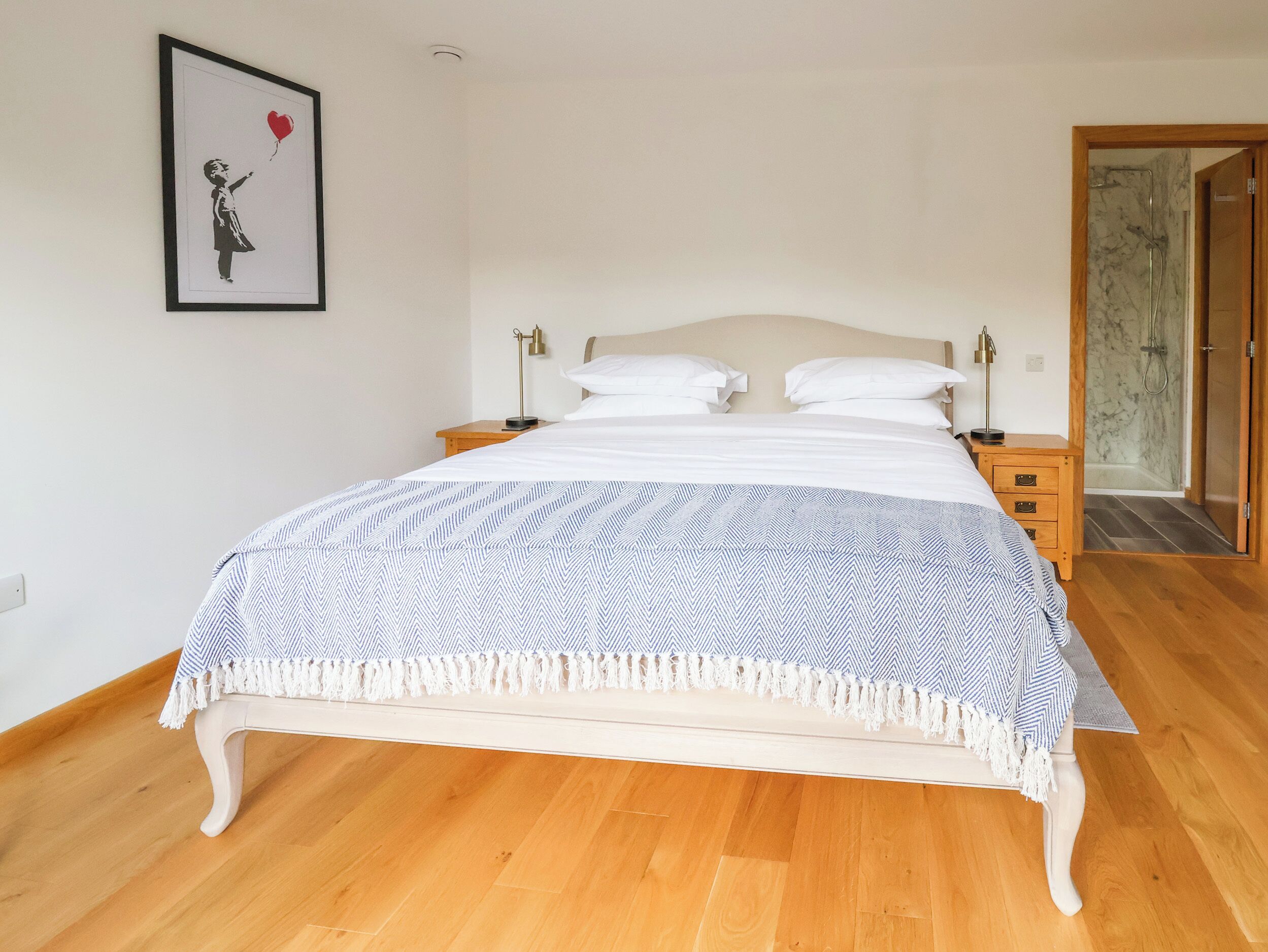 Une chambre à coucher avec un lit, une table de chevet, une lampe et un tableau encadré au mur.