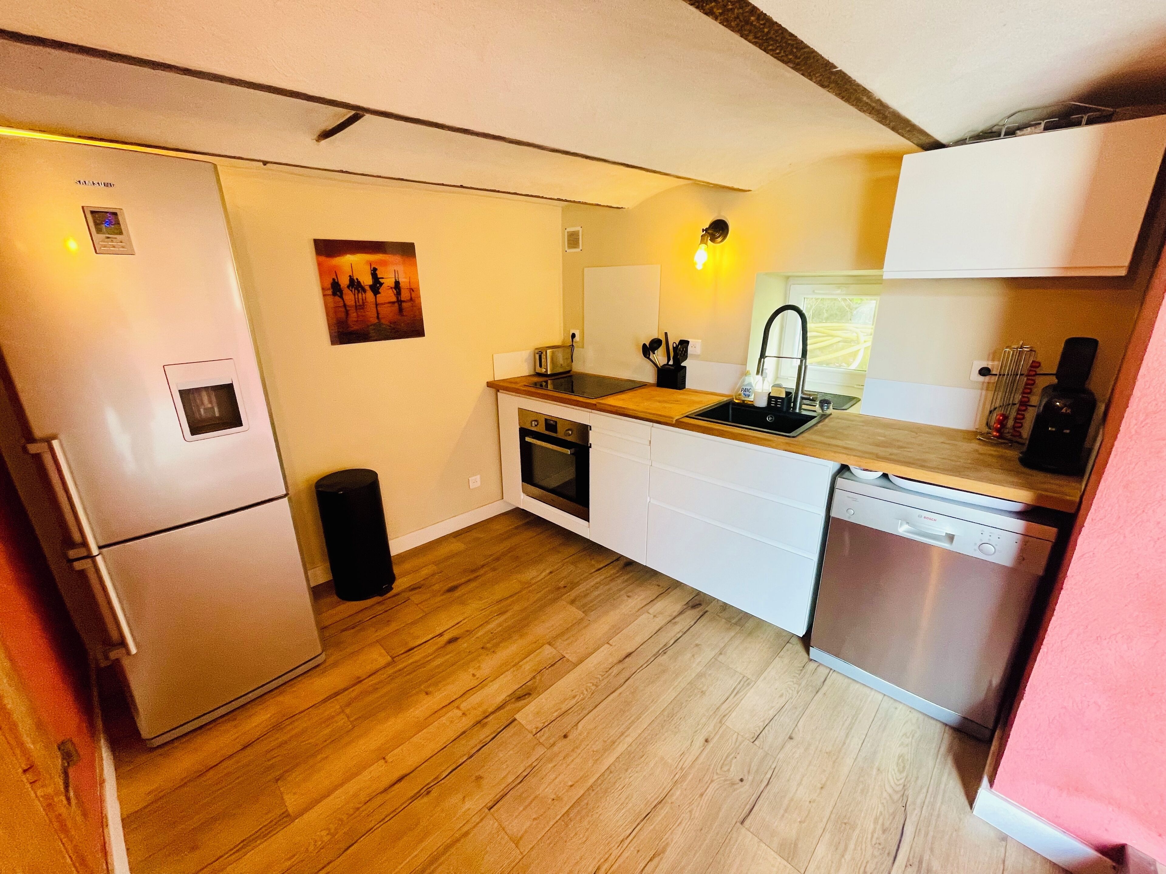 Eine kompakte Küche mit Kühlschrank, Backofen, Spüle und Geschirrspüler.