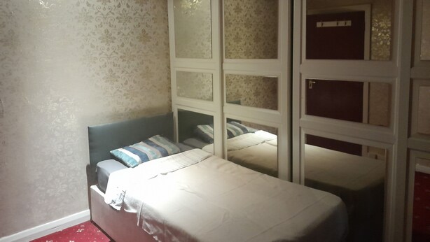 A bedroom with two beds, a wardrobe with glass doors, and patterned wallpaper. - Lovely 1-bed Studio in London (London)