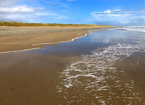A beach with wet sand and gentle waves. - Saltee View Holiday Home (Kilmore)