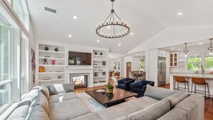 A spacious living room with a large sectional sofa, a fireplace, and a modern chandelier.