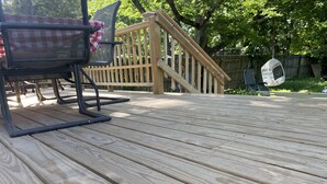 Une terrasse en bois avec une chaise en métal et une petite table.