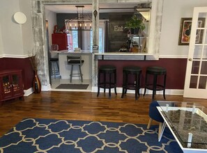 A modern kitchen with a bar area, wooden flooring, and a blue patterned rug. - Franklin Historic Cottage on Old Womack Distillery (Franklin)