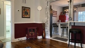 Un salon avec une cheminée, un coin repas avec un bar, et une cuisine visible à travers une porte ouverte.