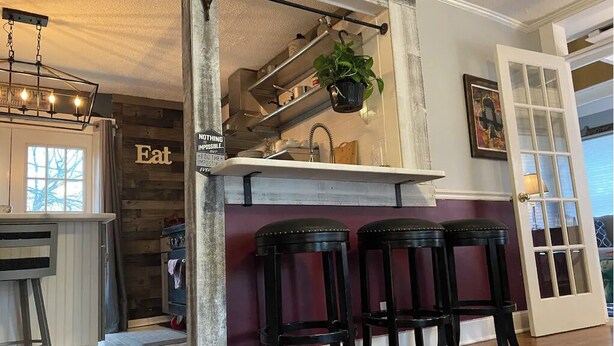 Une cuisine avec un plan de travail blanc, des plantes suspendues et un panneau « Manger » accroché au mur.
