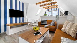 Uma sala de estar moderna com televisão de tela plana, mesa de centro de madeira e um sofá.