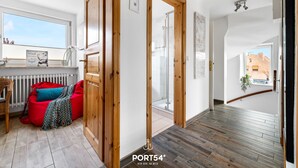 Interior moderno com piso de madeira, um bean bag vermelho e vista para um edifício de tijolos.