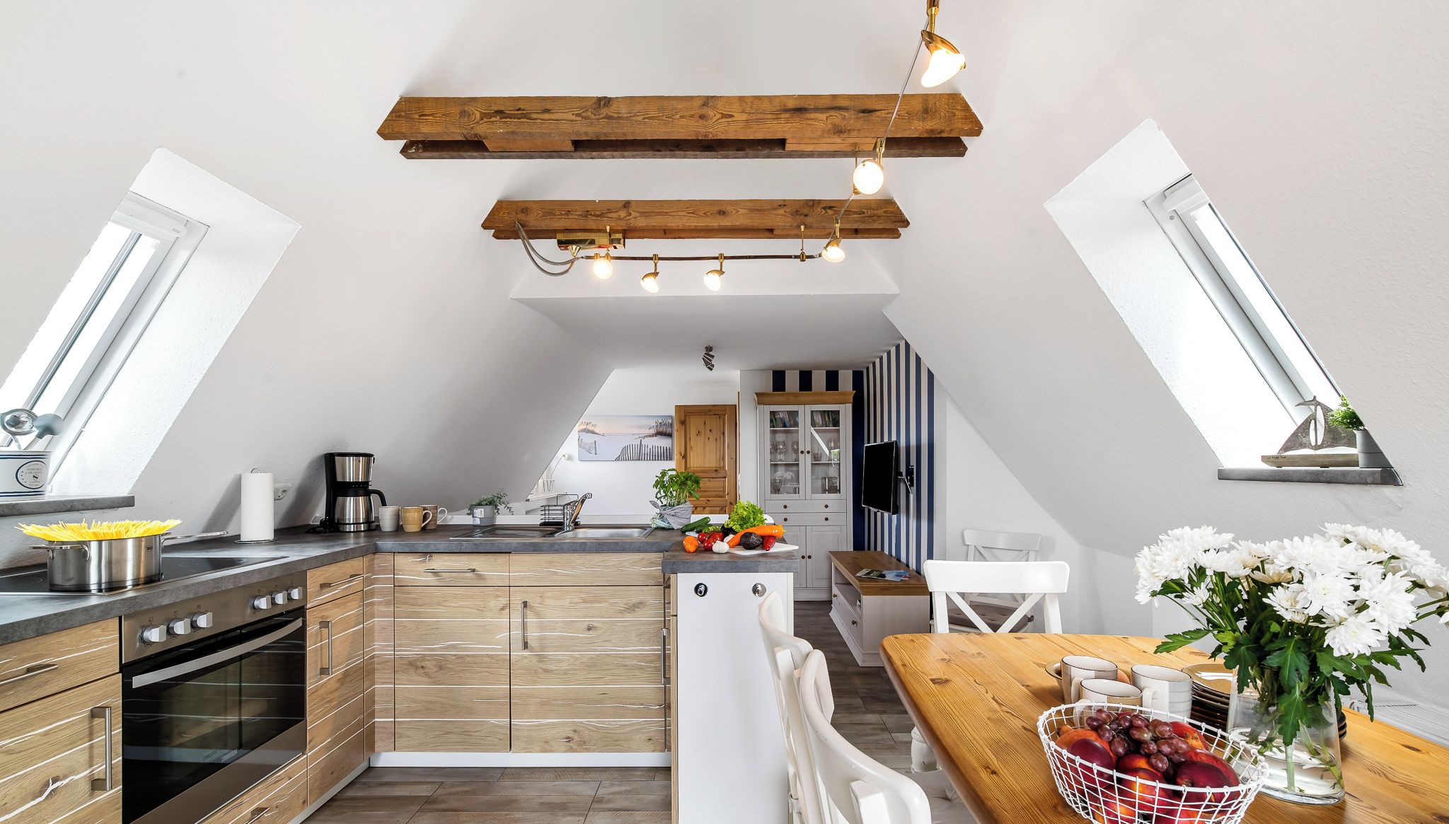 A modern kitchen with wooden cabinets, a built-in oven, and a dining area with a wooden table and chairs.