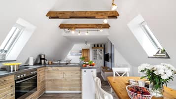 A modern kitchen with wooden cabinets, a built-in oven, and a dining area with a wooden table and chairs.