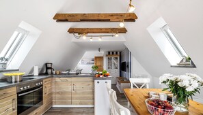 Une cuisine moderne avec des meubles en bois, un four encastré et un coin repas comprenant une table et des chaises en bois.