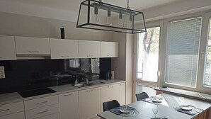 Une cuisine moderne avec des meubles blancs, un plan de travail noir et un coin repas avec une table mise pour deux personnes.