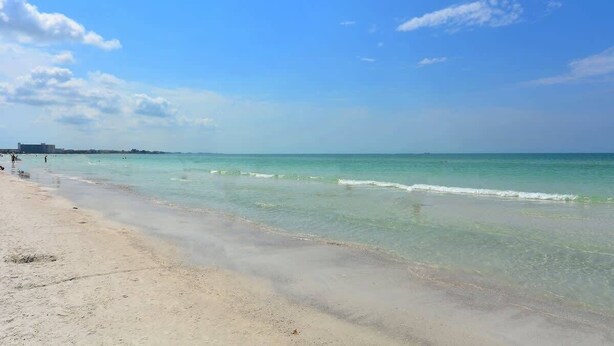 A beach with clear turquoise water, a sandy shore, and a few people in the distance. - Haven Hideaway with Saltwater Pool 3br Sleeps 8 (Sarasota)