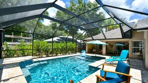 A swimming pool with a glass enclosure, surrounded by lounge chairs and a patio area. - Haven Hideaway with Saltwater Pool 3br Sleeps 8 (Sarasota)