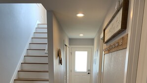 A hallway with a wooden staircase, a bench, a door, and a small window. - Daybreeze Vacation Home w/ Hot Tub & Gorgeous View (Homer)