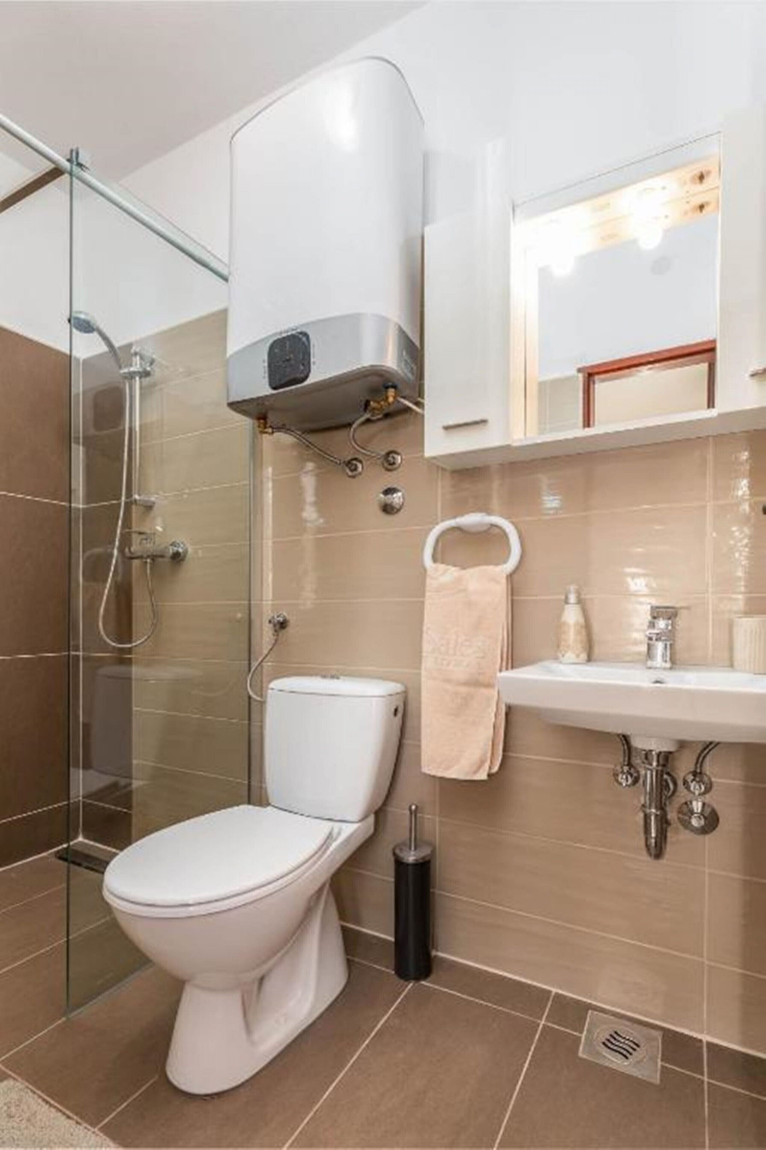 Een moderne badkamer met een douchecabine van glas, een wit toilet en een wastafel met handdoekrek.