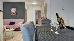 Ein Wohnbereich mit einer Couch, einem Couchtisch und einer Weinflasche auf einem Tisch.