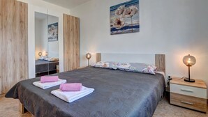 Ein modernes Schlafzimmer mit einem großen Bett, einem Holzschrank und einem Nachttisch mit Lampe.