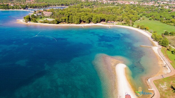 Vista aérea de una zona costera con playa, aguas cristalinas y vegetación circundante.