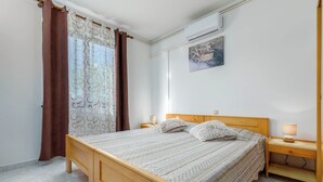 Un dormitorio con cama de madera, mesita de noche, aire acondicionado de pared y un cuadro de una bicicleta.