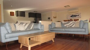 A modern living room with two light blue sofas, a wooden coffee table, and a kitchen in the background. - Lady Doris,  wifi  - Off Peak Special! (Port Vincent)