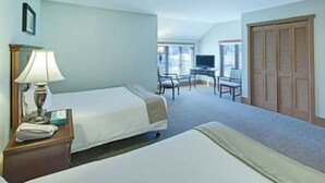 Ein Hotelzimmer mit zwei Betten, einem Schreibtisch mit Stuhl, einem Fernseher und einem Schrank.