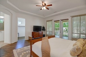 A bedroom with a large bed, a ceiling fan, a television, and a view of the outdoors through the windows. - Big Yard REAL Grass Open Floor Plan Total Privacy (Indio)