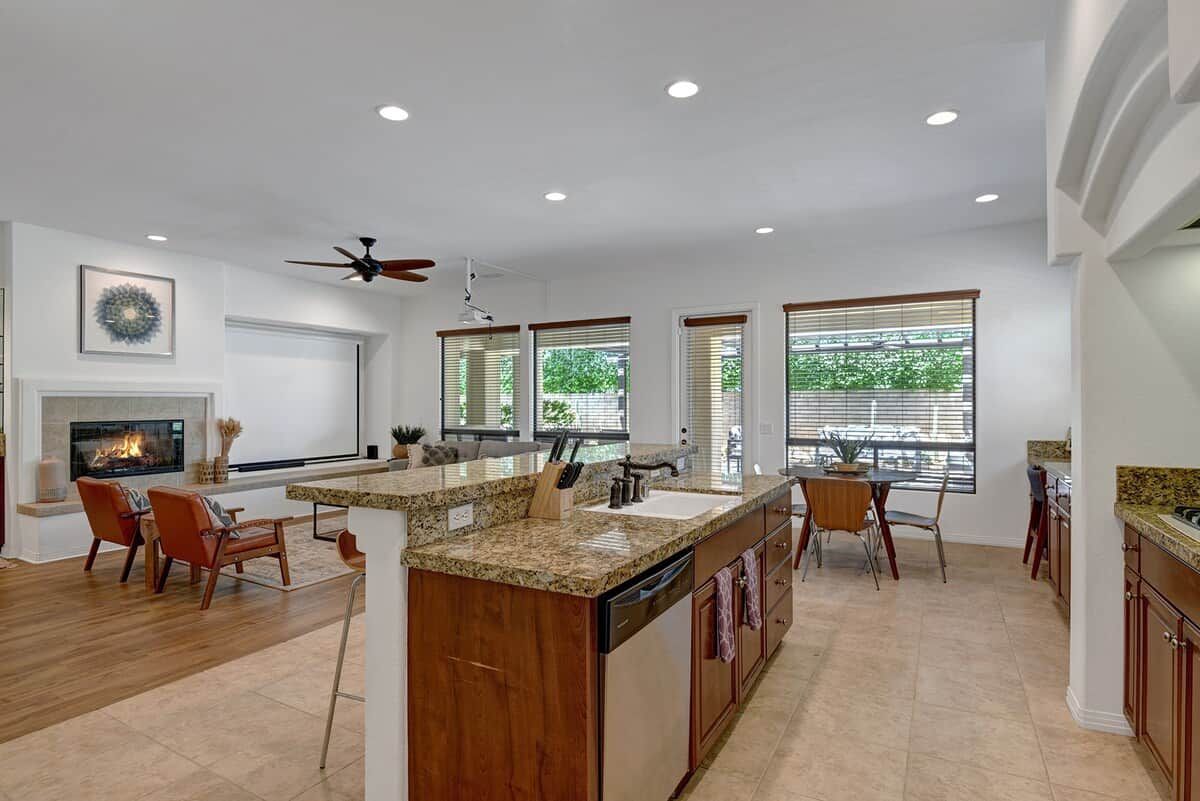 A spacious kitchen with a central island, wooden cabinets, and a built-in dishwasher.