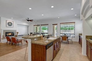 A spacious kitchen with a central island, wooden cabinets, and a built-in dishwasher.