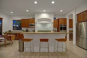 A modern kitchen with wooden cabinets, stainless steel appliances, and a central island with bar stools.