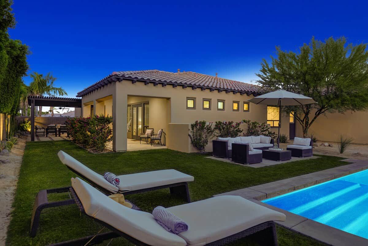 A residential property with a swimming pool, outdoor seating, and a covered patio area.