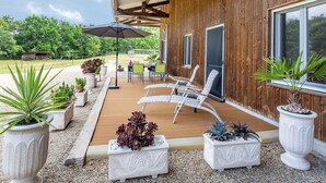 Eine Terrass mit Holzdeck, weißen Lounge-Stühlen und Pflanzkästen mit verschiedenen Pflanzen.