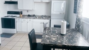 Une cuisine de taille réduite avec des meubles blancs, une cuisinière, un évier et un lave-linge.