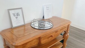 Une console en bois avec un plateau en verre et des documents encadrés.