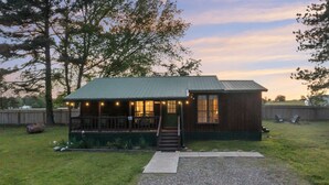 A wooden cabin with a porch and a staircase leading to the entrance. - 2Br Cabin with hot tub, BBQ, 55" Smart TV, W/D. (Broken Bow)
