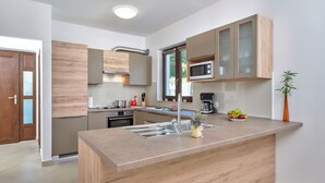 A modern kitchen with a central island, stainless steel appliances, and wooden cabinetry.