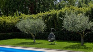 A swimming pool with a clear blue water surface, surrounded by well-maintained grass and hedges.