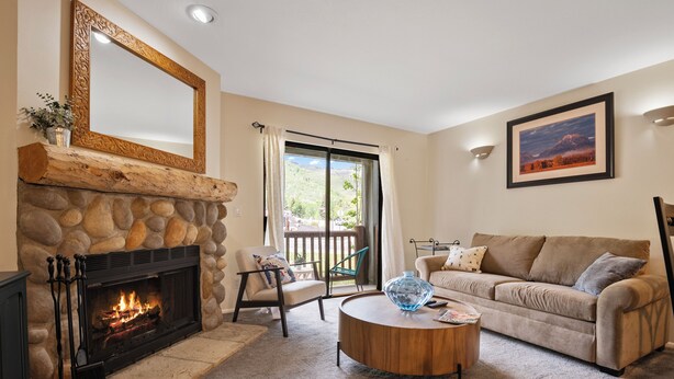 A living room with a stone fireplace, a sofa, a coffee table, and a painting on the wall.