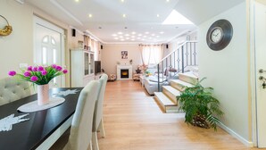 A spacious living area with a dining table, chairs, a fireplace, and a staircase leading to an upper floor. - Luxury House Anita in old Town Cavtat-beachfront (Konavle)