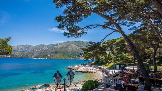 A coastal outdoor seating area with tables and chairs, overlooking a clear blue sea and a rocky shoreline. - Luxury House Anita in old Town Cavtat-beachfront (Konavle)