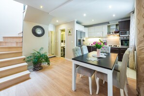 Et moderne køkken med hvide skabe, et spisebord med stole og en trappe op til en etage.