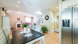 A modern kitchen with a stainless steel refrigerator, a dining area with a table and chairs, and a staircase leading to another level. - Luxury House Anita in old Town Cavtat-beachfront (Konavle)