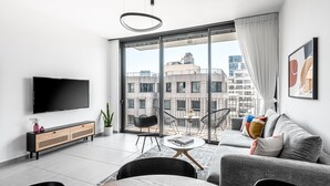Een moderne woonkamer met een grote televisie, een bank en een eethoek.
