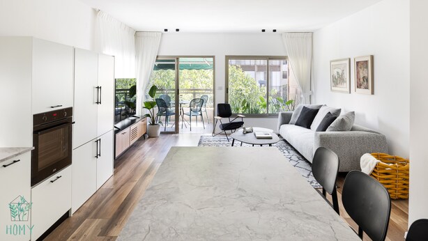Een moderne keuken met inbouwapparatuur, een eethoek met een marmeren tafel en een zithoek met een bank en stoelen.