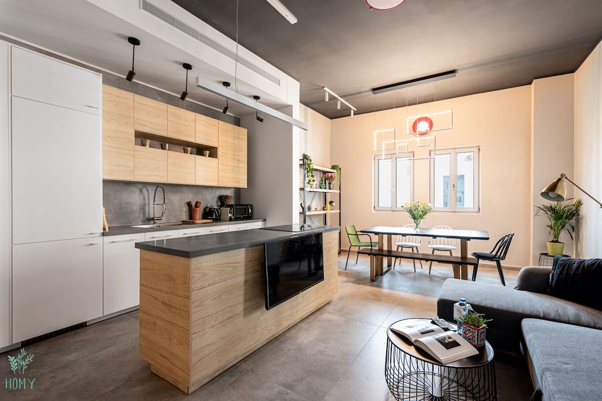 A modern kitchen with a central island, wooden cabinets, and a dining area with a table and chairs.