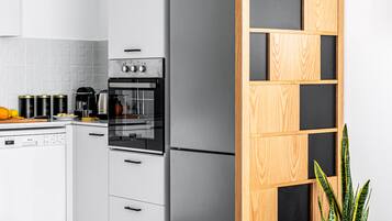 A modern kitchen with white cabinetry, a built-in oven, and a wooden partition with black panels.